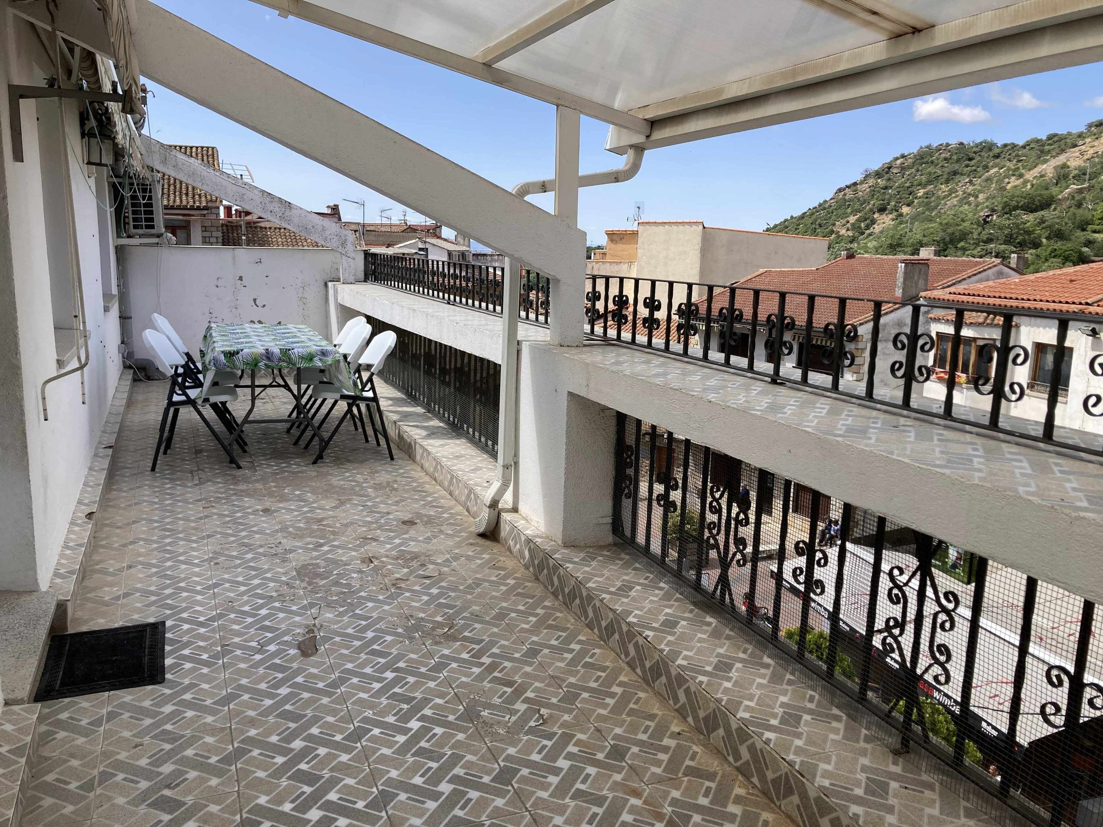 Un balcon avec un sol carrelé, une table avec des chaises et une rambarde.