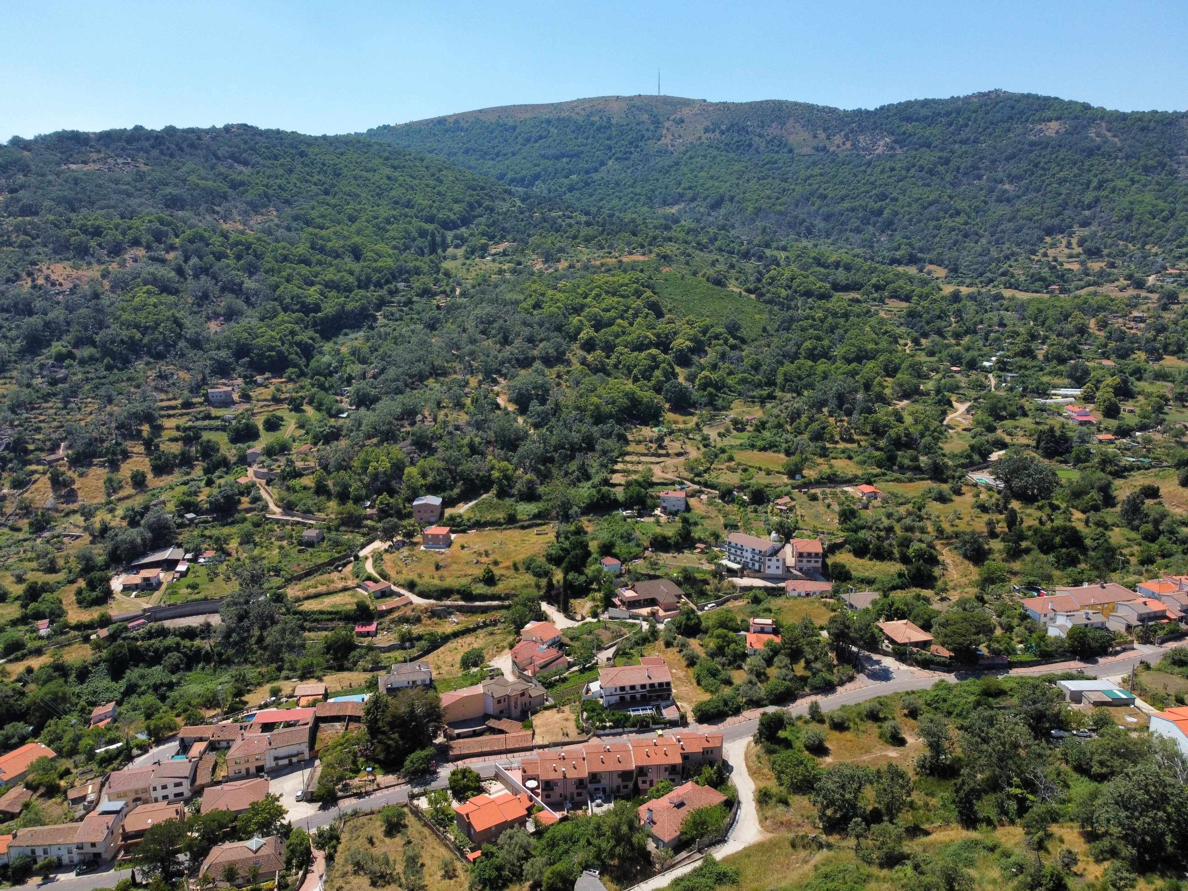 Un village rural avec des maisons et une colline en arrière-plan.