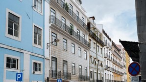 Eine Reihe mehrstöckiger Gebäude mit Balkonen, darunter ein blaues Gebäude mit einem 'P'-Parkschild und einem Verbotsschild für Fahrzeuge.
