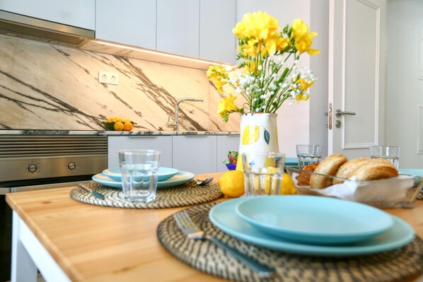 Enjoy meals in this kitchen with a dining table, vase, and fresh flowers.