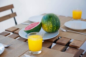 A table with a plate of watermelon, a glass of orange juice, and a fork. - Her Majesty at Liverdade Avenue 1E (Lisbon)