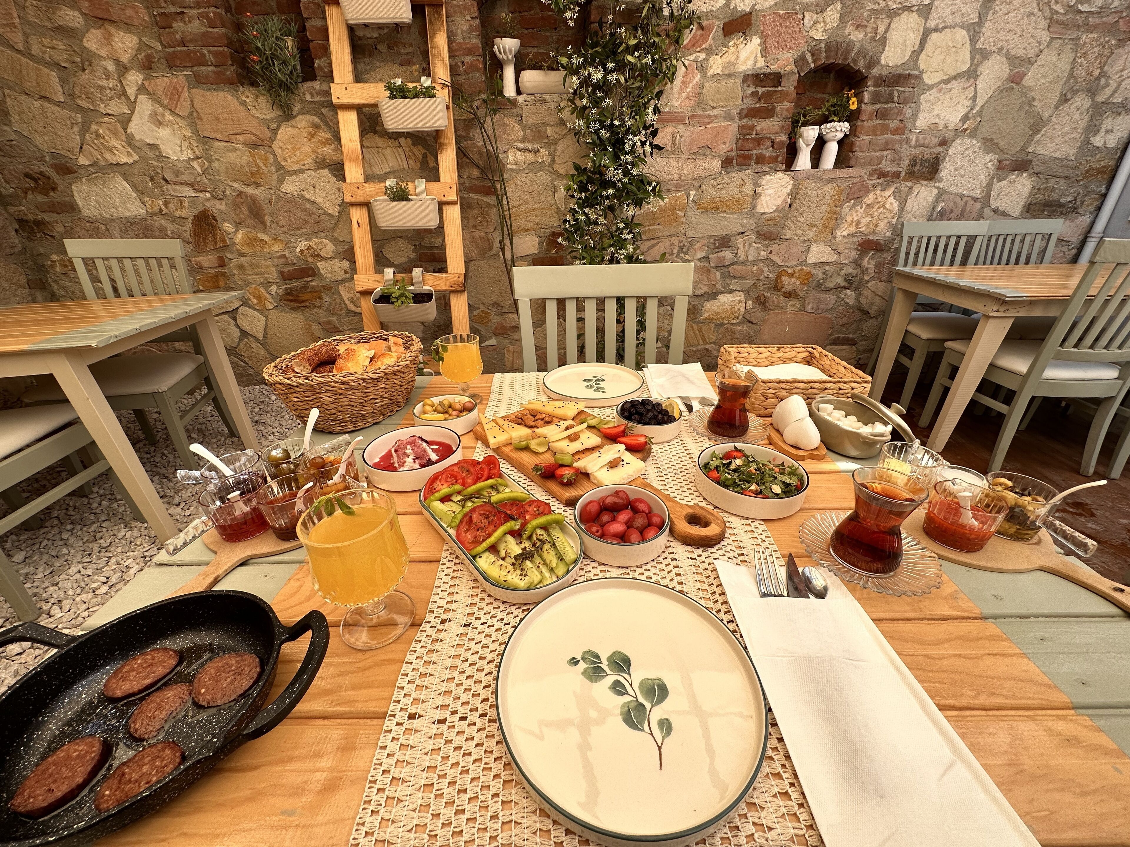 Un espacio al aire libre para comer con paredes de piedra, muebles de madera y una variedad de alimentos y bebidas.