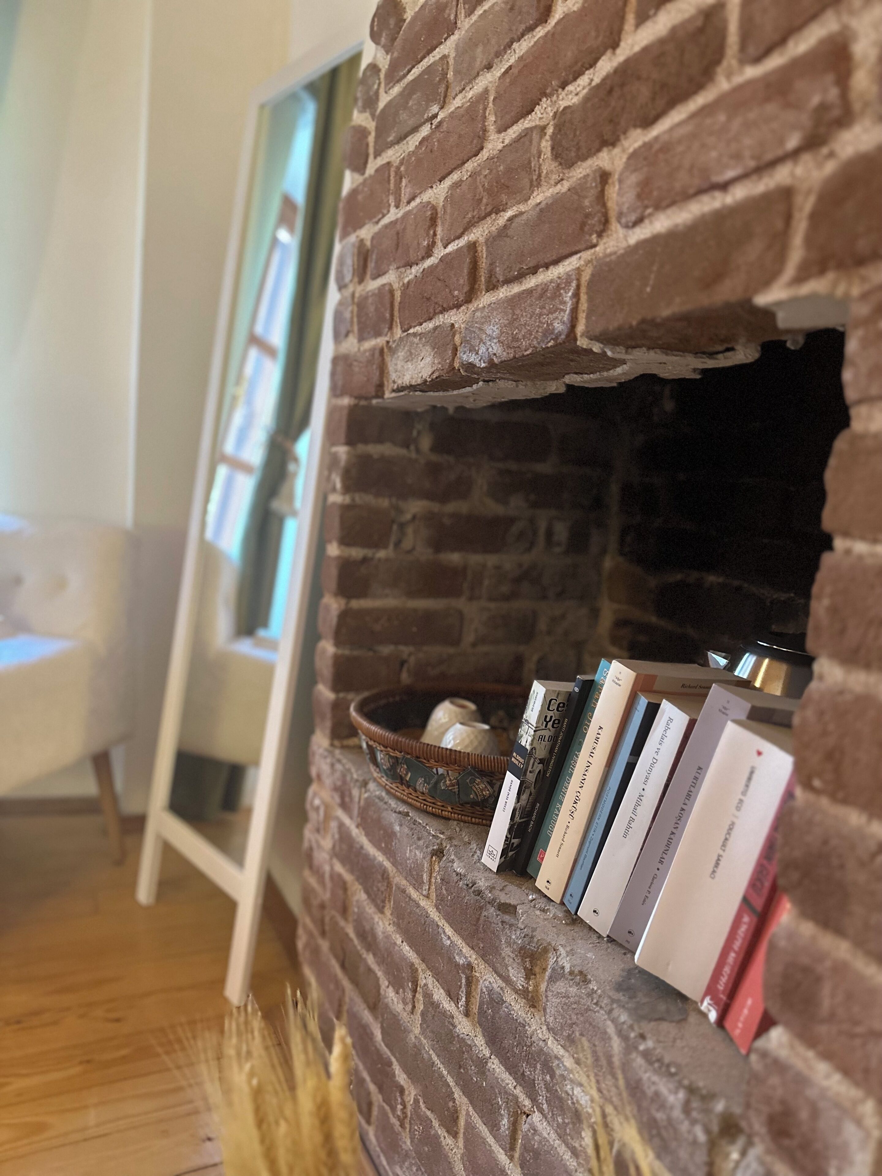 Una chimenea de ladrillo con libros y una cesta.