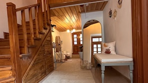 A wooden staircase leading to a living area with a white rug, a bench, and a brick oven. - Hanole Guest House (Ayvalik)