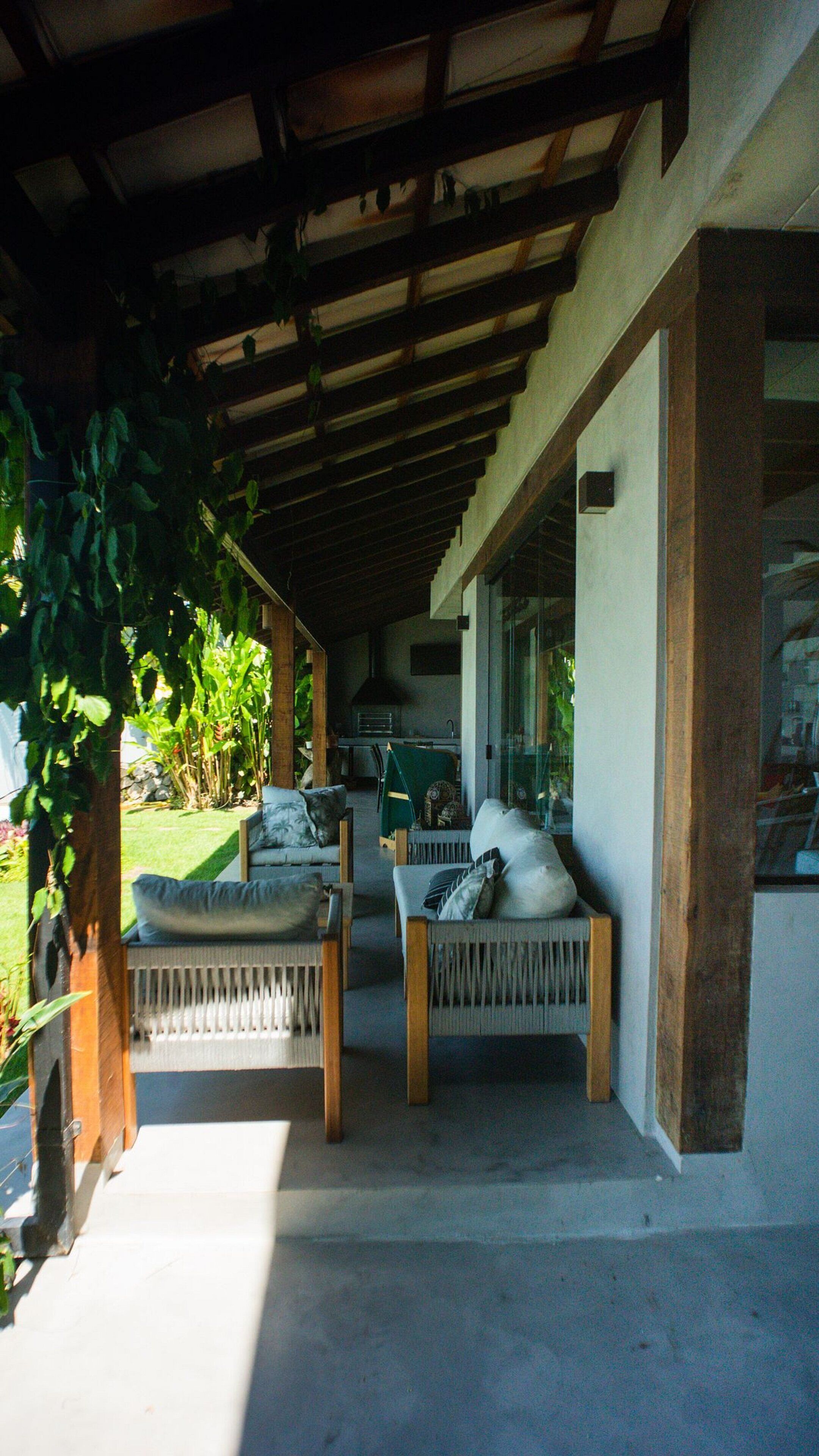 An outdoor seating area with two chairs and a table, a covered patio, and a view of the garden.