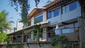 A multi-story building with balconies, large windows, and a mix of modern and traditional architectural elements. - Casa pé na areia com piscina | São Sebastião (São Sebastião)