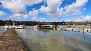A marina with several boats docked, a wooden pier, and a backdrop of trees and buildings. - Byewater (Ryde)