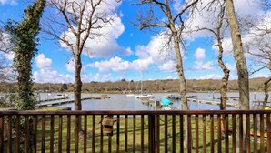 A lakeside view with docked boats, a wooden deck, and trees. - Byewater (Ryde)