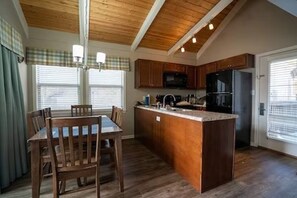 Enjoy meals in this kitchen with a central island and dining table for four, featuring a refrigerator, microwave, and ample counter space.