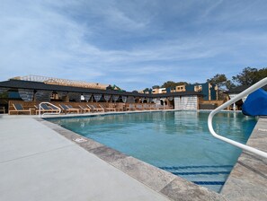 En pool med solstolar och ett överbyggt område.