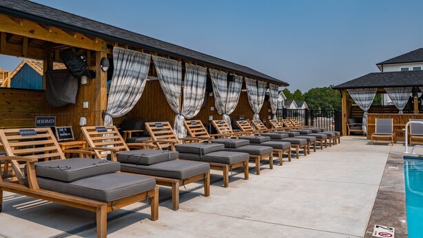 Zona junto a la piscina con sillones de madera y una piscina.