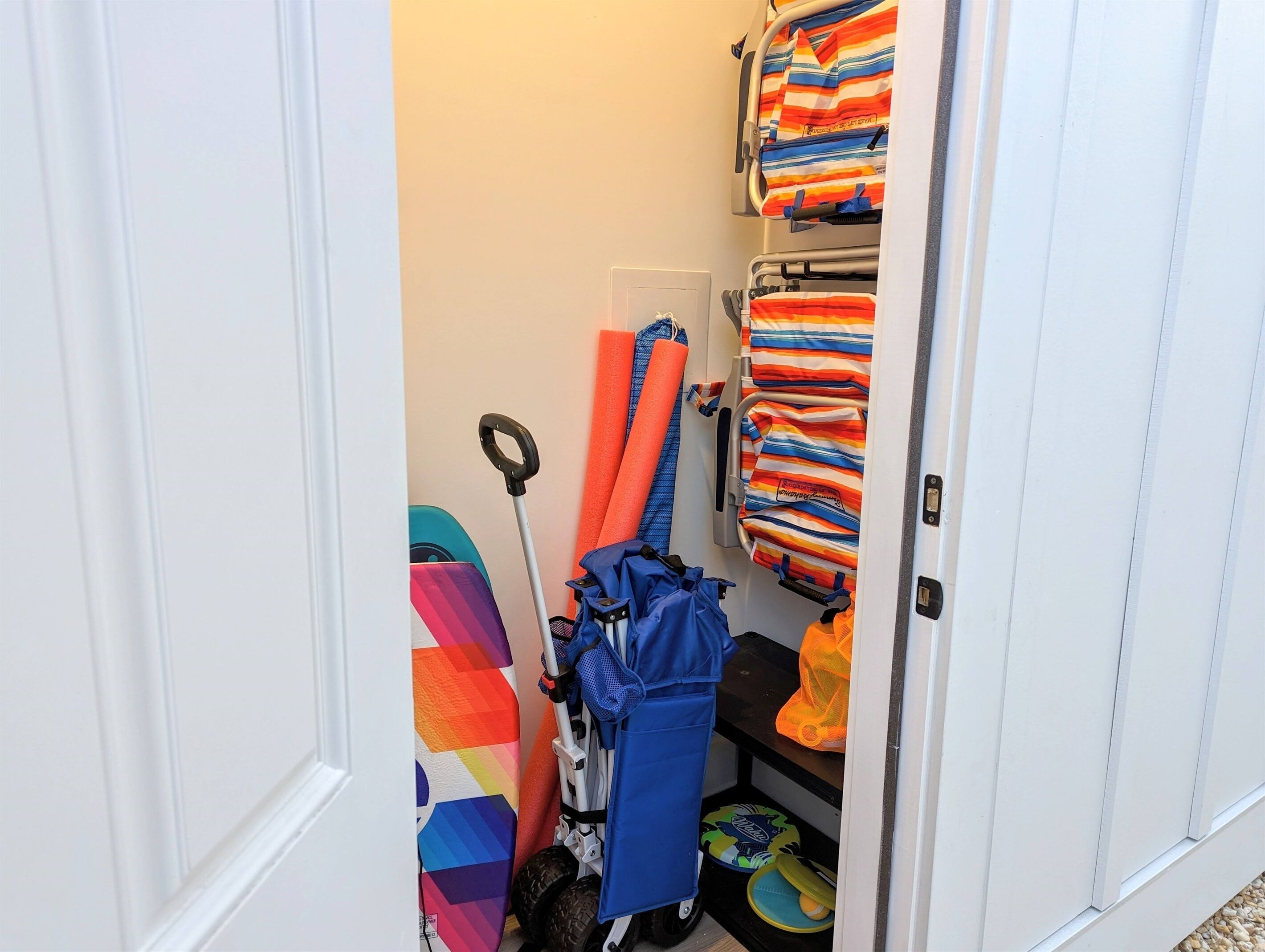 A narrow hallway with a stroller, a baby walker, and folded blankets on shelves.