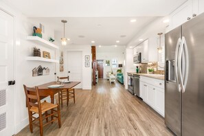Eine moderne Küche mit weißen Schränken, einem Edelstahlkühlschrank und Holzböden.