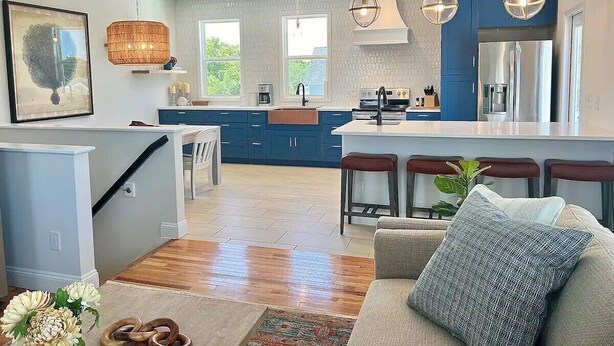 Een moderne keuken met blauwe kastjes, een centraal eiland en hanglampen.