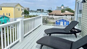 Een balkon met twee zwarte loungestoelen, een witte balustrade en uitzicht op gebouwen en een reuzenrad in de verte.