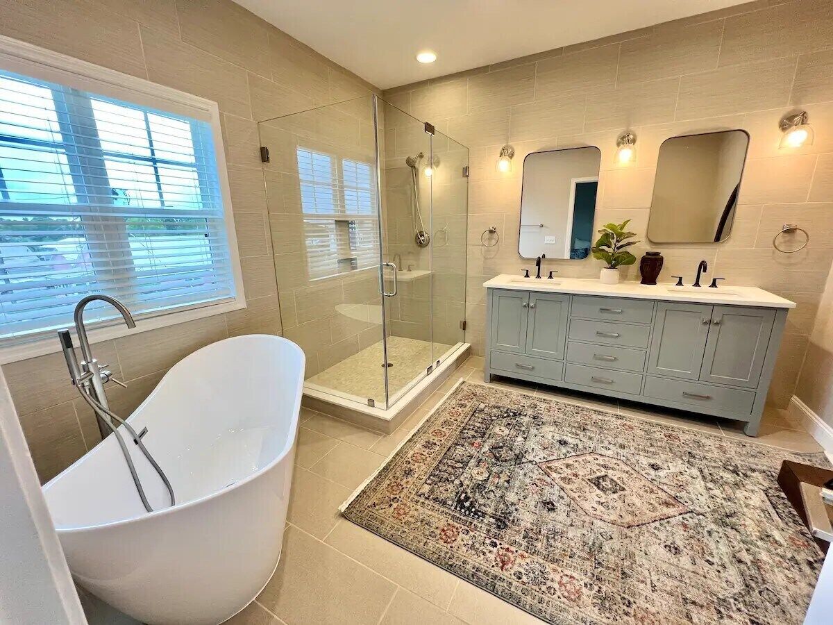Une salle de bain moderne avec une baignoire sur pieds, une douche à l’italienne et un meuble-lavabo avec un miroir.