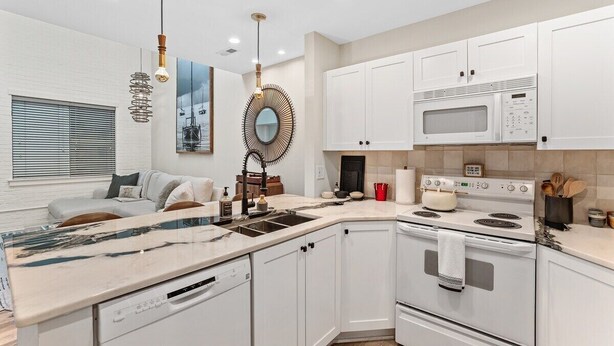 A modern kitchen with white cabinetry, a built-in oven, a microwave, and a large island with a sink. - Chic Downtown Loft - Parking - Central New (Wilmington)