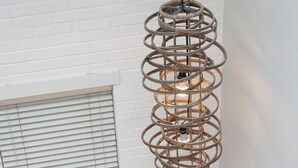 A room with a white brick wall, a window with blinds, a woven pendant light fixture, and a sofa with cushions. - Chic Downtown Loft - Parking - Central New (Wilmington)