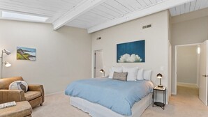 A bedroom with a large bed, a brown leather chair, a small table with a lamp, and a painting on the wall. - Chic Downtown Loft - Parking - Central New (Wilmington)