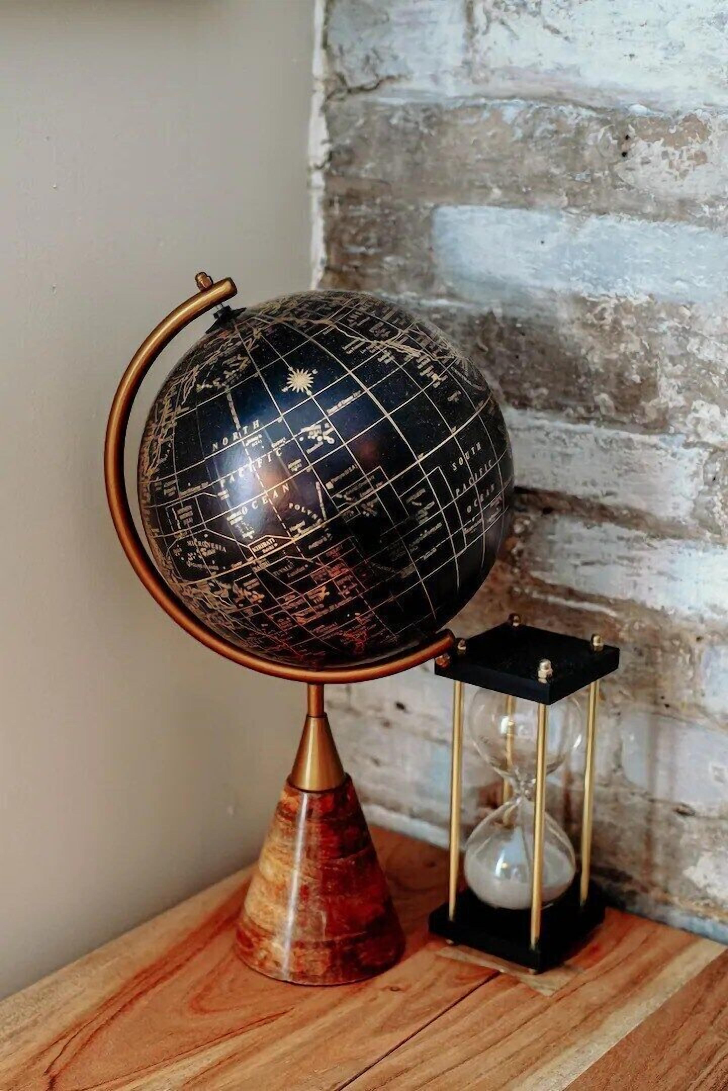 Un globe terrestre posé sur un socle en bois, avec un petit sablier à côté.