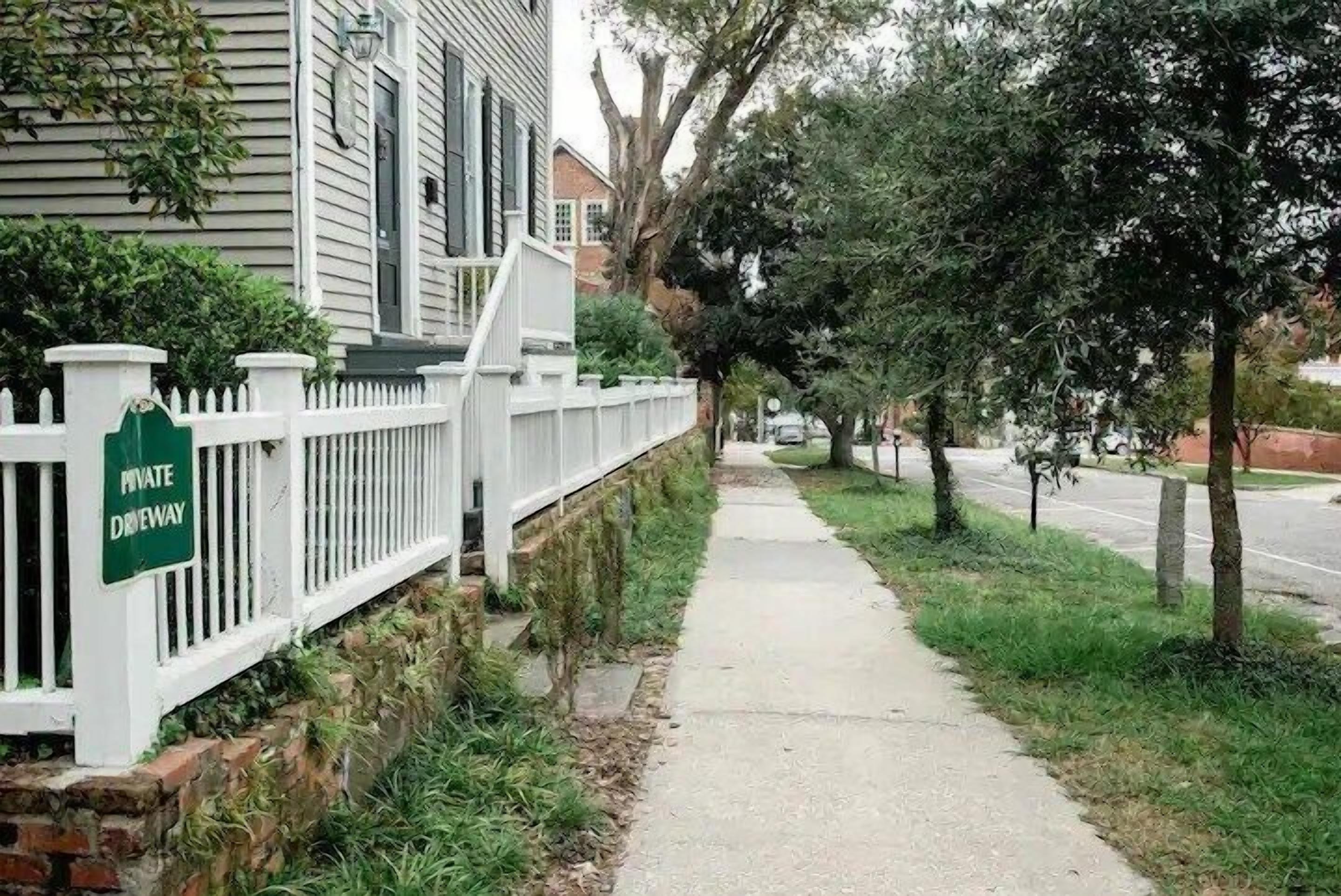 A sidewalk adjacent to a white fence with a sign reading "PRIVATE DRIVEWAY."