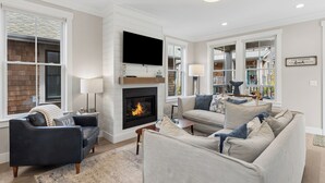 A living room with a fireplace, a television, and a sofa. - Seabrook Cypress and Sand | Hot Tub, Park Views | 3BR, Sleeps 8, Cedar Run Park (Pacific Beach)