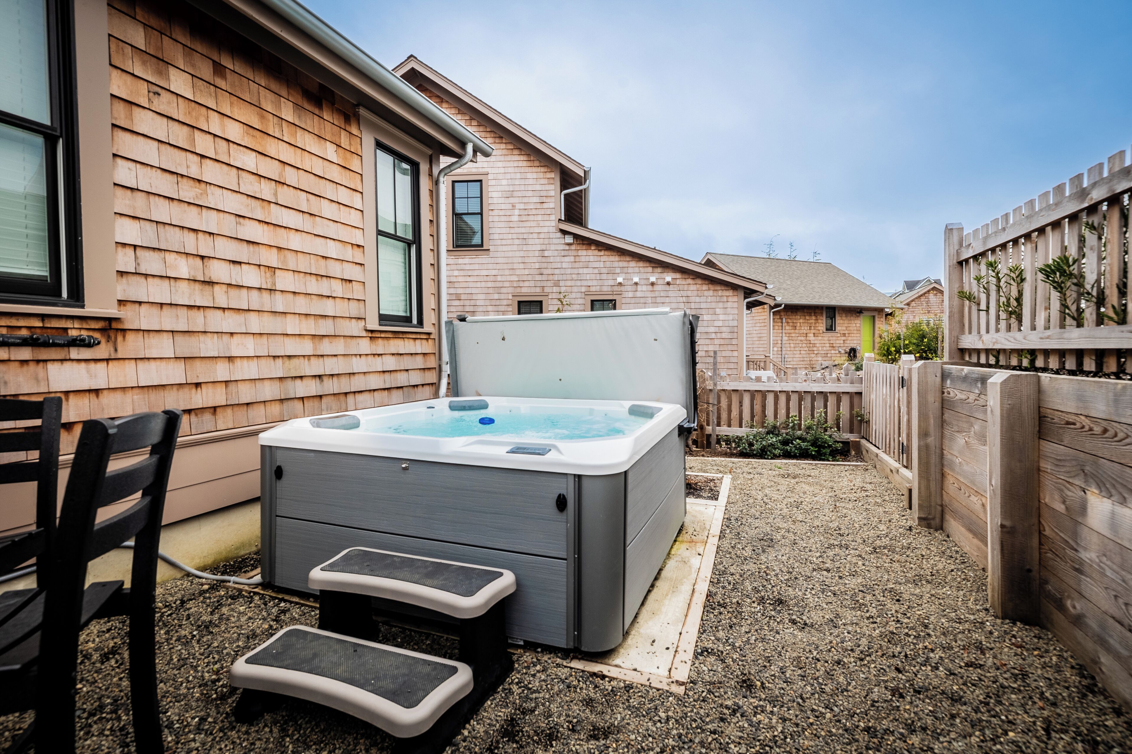 Een hottub met treden, een houten terras en een huis met raam en deur.