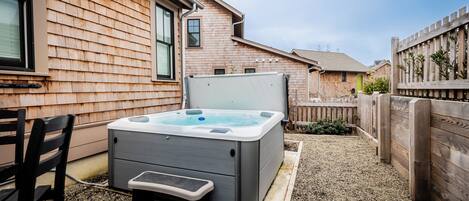 Een hottub met treden, een houten terras en een huis met raam en deur.