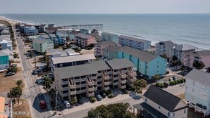 Ein Küstenwohngebiet mit mehrstöckigen Gebäuden, einer Pier, die sich ins Meer erstreckt, und freiem Blick auf den Strand.