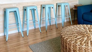 Eine Küche mit weißer Arbeitsplatte, vier blauen Barhocker, einer Mikrowelle und einem blauen Sofa.