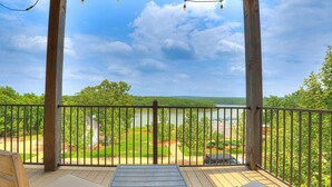 A wooden deck with two wicker chairs and a table, overlooking a lake and greenery. - Residence Club Unit 6 in Carlton Landing (Carlton Landing)