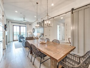 Un comedor amplio con una mesa de madera, sillas de mimbre y un gran jarrón como centro de mesa.