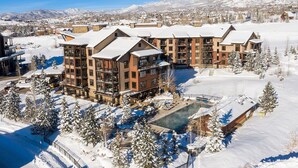 Una località turistica innevata con diversi edifici, una piscina e montagne sullo sfondo.