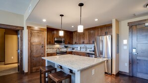 Una cucina moderna con mobili in legno, elettrodomestici in acciaio inossidabile e un'isola centrale con sgabelli.