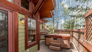 A wooden deck with a hot tub, a wooden door, and a view of trees. - Mountain Escape at Paloverde – Spacious 4-Bedroom Retreat with Private Hot Tub! (Steamboat Springs)