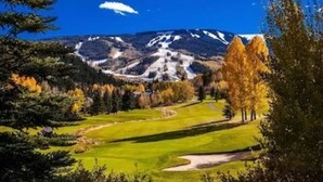 Een golfbaan met een berg op de achtergrond en herfstkleuren.