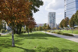 A park with a pathway, trees, and modern buildings in the background. - Radisson Hotel Budapest Budapart (Budapest)