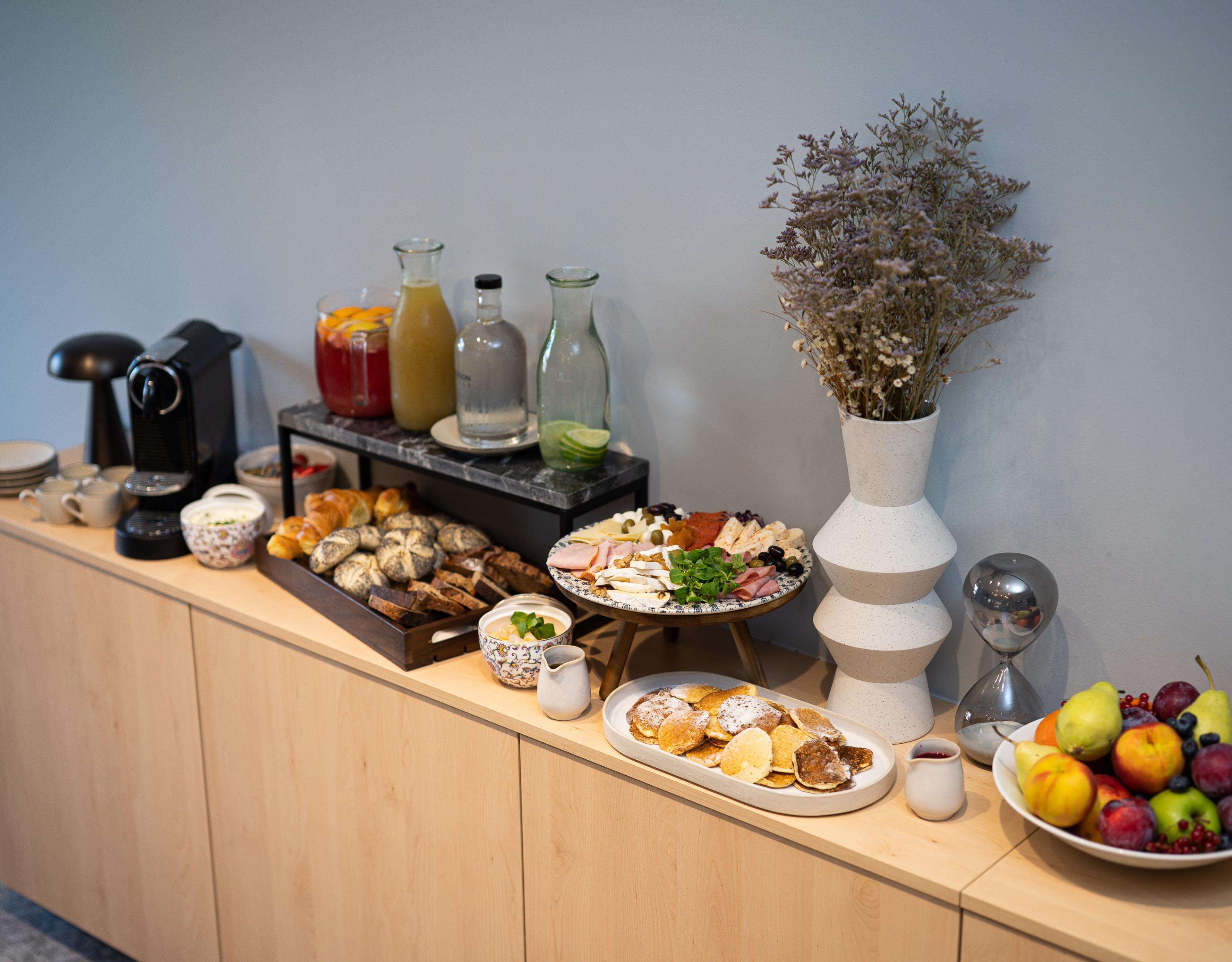 A buffet table with various food items, including pastries, cheeses, and fruits.