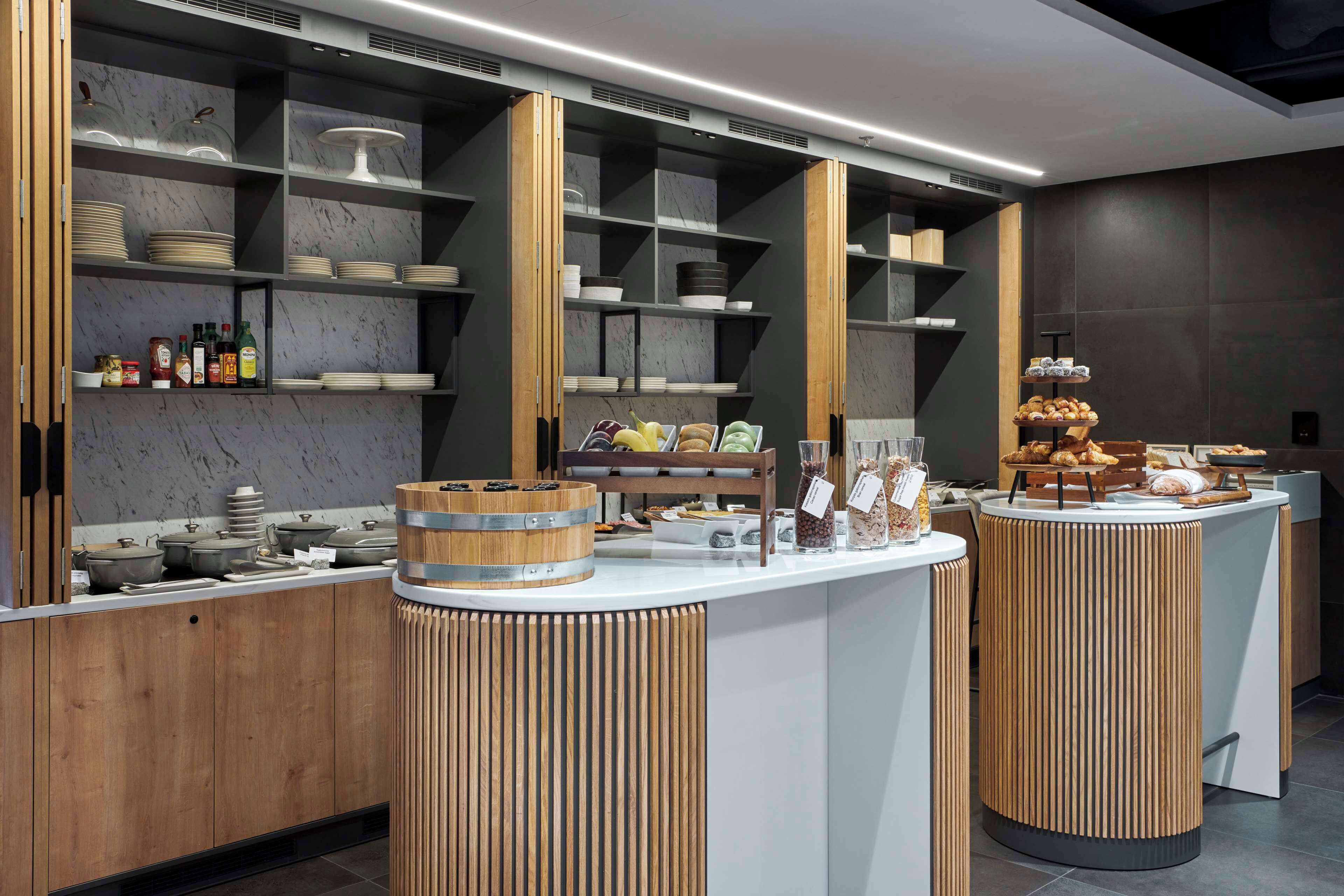 A modern breakfast bar with marble shelves, wooden accents, and a variety of food items.