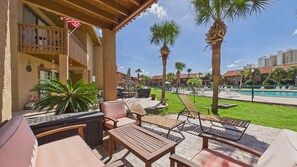 A poolside area with lounge chairs, a barbecue grill, and a view of a swimming pool and palm trees. - Paradise Pointe 137–5 Min to Beach–Sleeps 6 (Panama City Beach)