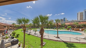 A pool area with palm trees, lounge chairs, and a view of a cityscape. - Paradise Pointe 137–5 Min to Beach–Sleeps 6 (Panama City Beach)