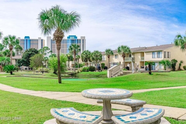 A courtyard with a central mosaic fountain, surrounded by palm trees and a pool. - Paradise Pointe 137–5 Min to Beach–Sleeps 6 (Panama City Beach)