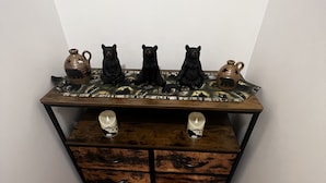 A corner table with three ceramic bear figurines and two candles, set against a white wall.
