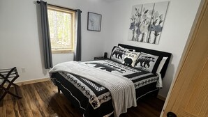 A bedroom with a bed, a ceiling fan, a window with curtains, and a door.