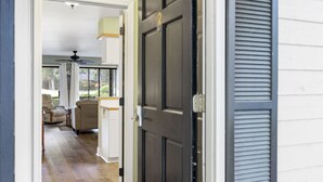 Ein Flur, der in einen Wohnbereich führt, mit Deckenventilator, einer Tür mit einer Nummer und einem Fenster mit Jalousien.