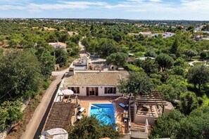 A residential property with a swimming pool, a covered patio, and a view of the surrounding landscape.
