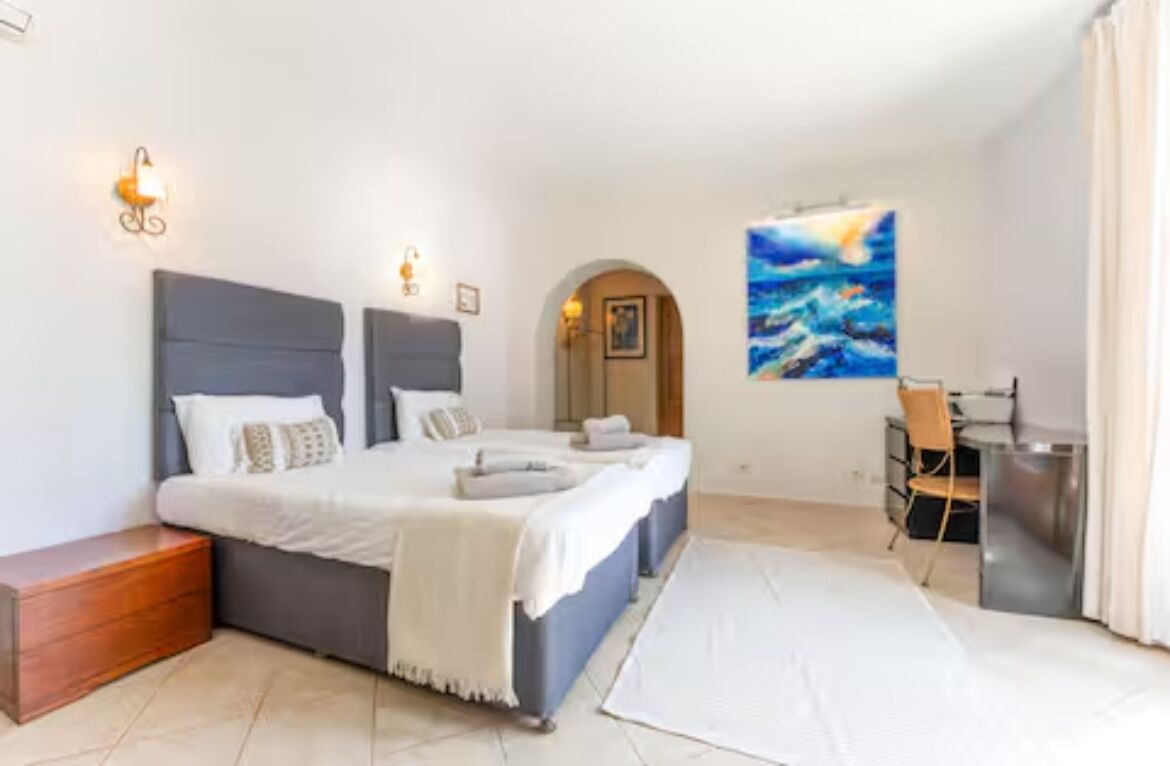 Une chambre à coucher avec un lit, des tables de chevet, un bureau et une chaise.