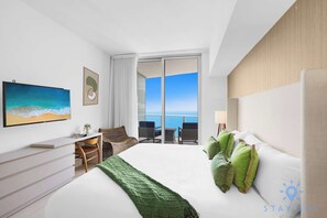 A modern hotel room with a large bed, a desk, a chair, and a view of the ocean. - Upper Level Penthouse: Beach & Intercostal Views (Hollywood)