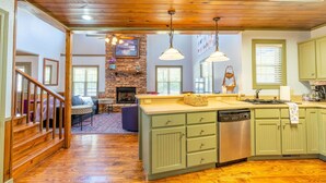 A spacious kitchen with wooden flooring, green cabinets, and a central island. - Beautiful, Bright Home Steps From Little Red River (Heber Springs)