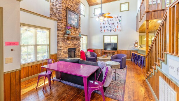 A spacious living area with a stone fireplace, wooden floors, and a high ceiling with exposed beams. - Beautiful, Bright Home Steps From Little Red River (Heber Springs)